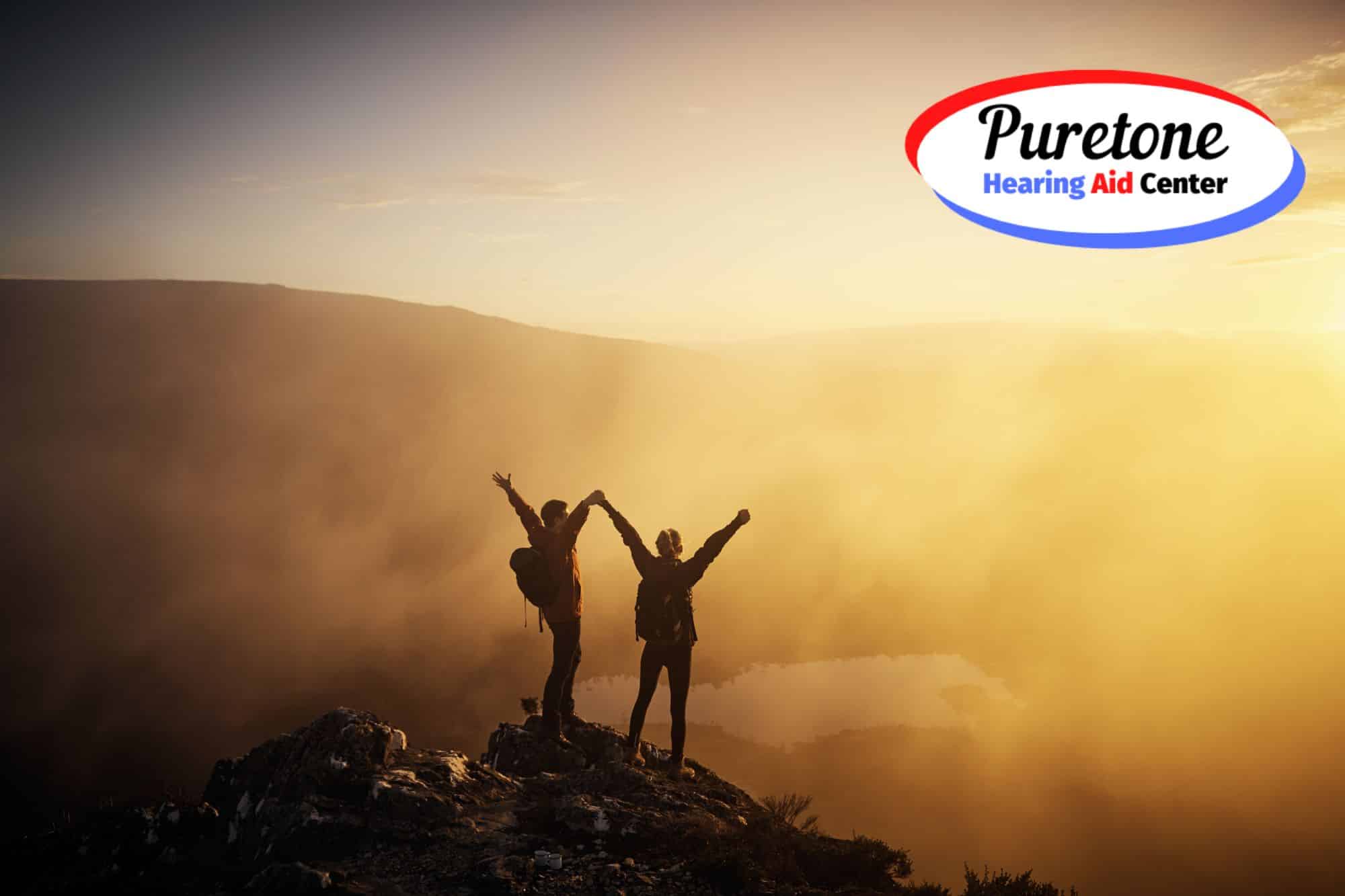 two people holding hands on top of a mountain